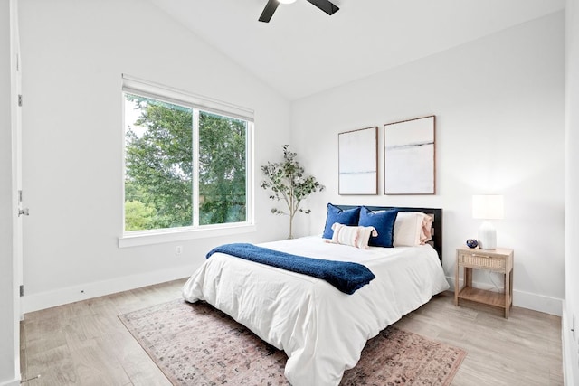 bedroom with light wood-style floors, multiple windows, vaulted ceiling, and baseboards