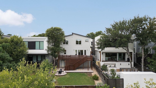 rear view of house featuring fence, stairway, a lawn, and stucco siding