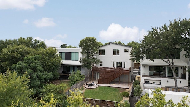 rear view of property with fence private yard, stairway, a lawn, and stucco siding