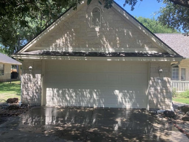 view of side of home featuring a garage, roof with shingles, and fence