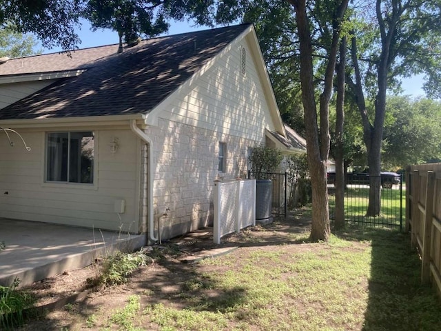 view of property exterior featuring a yard, roof with shingles, and fence