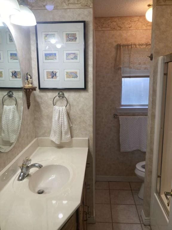 full bathroom featuring tile patterned flooring, toilet, vanity, baseboards, and a shower