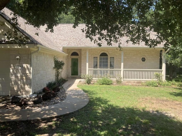 view of front of house with a garage, covered porch, roof with shingles, and a front lawn