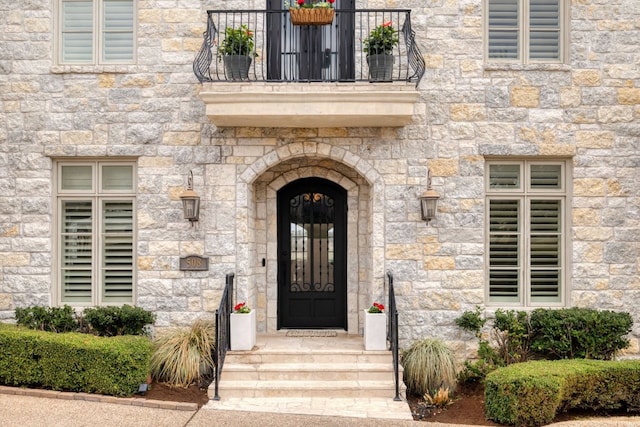 property entrance with stone siding and a balcony