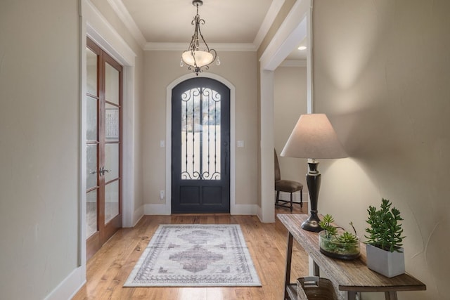 foyer entrance with arched walkways, light wood-style flooring, baseboards, french doors, and ornamental molding