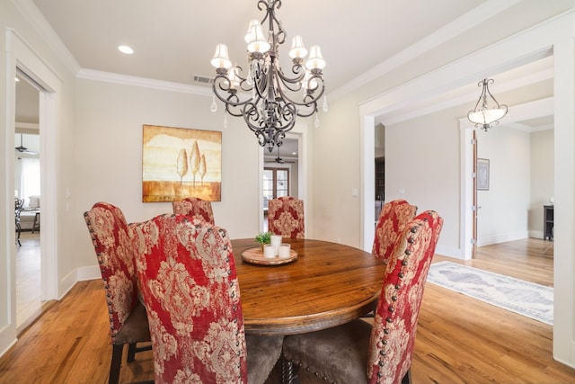 dining area with ornamental molding, visible vents, light wood-style flooring, and a ceiling fan