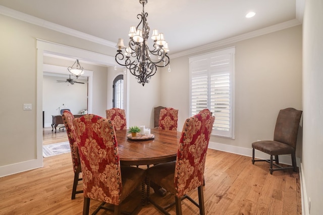 dining room featuring arched walkways, light wood finished floors, baseboards, and crown molding