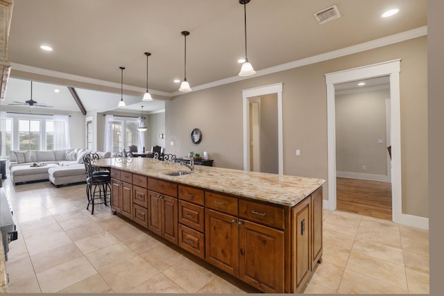 kitchen with baseboards, a breakfast bar area, open floor plan, light stone countertops, and a sink