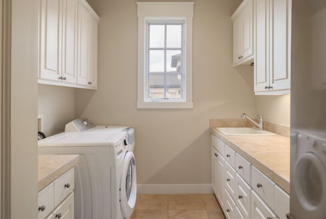 laundry room with cabinet space, light tile patterned floors, baseboards, washing machine and dryer, and a sink