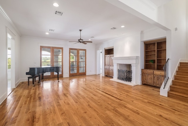 living area with ornamental molding, recessed lighting, a fireplace with raised hearth, french doors, and light wood-style flooring