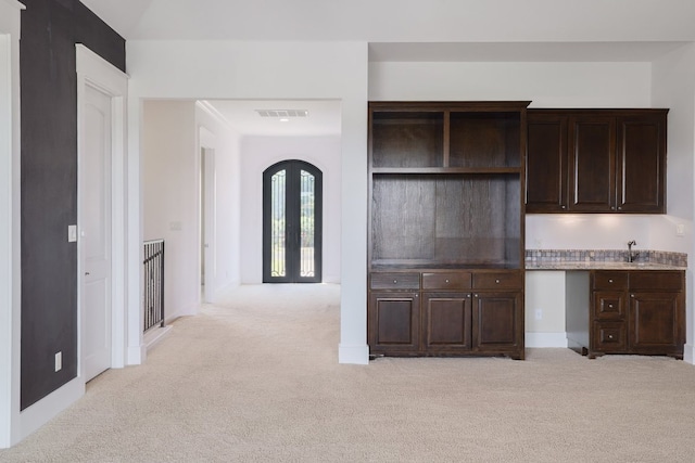 kitchen with dark brown cabinetry, visible vents, and light carpet
