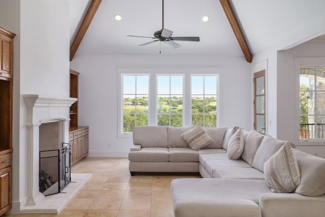 living area featuring a ceiling fan, a fireplace with raised hearth, plenty of natural light, and beam ceiling
