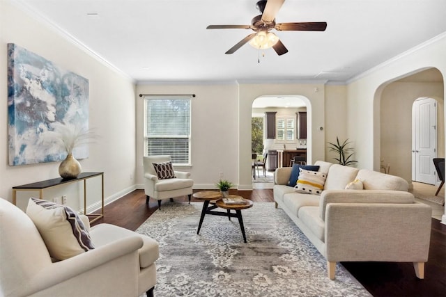 living room with ornamental molding, arched walkways, baseboards, and wood finished floors