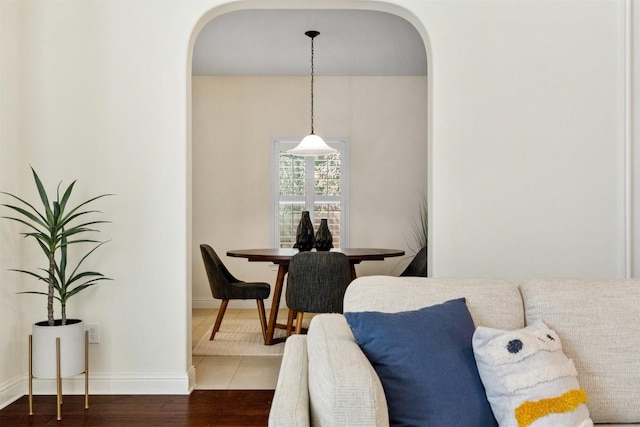 interior space with baseboards, arched walkways, and wood finished floors