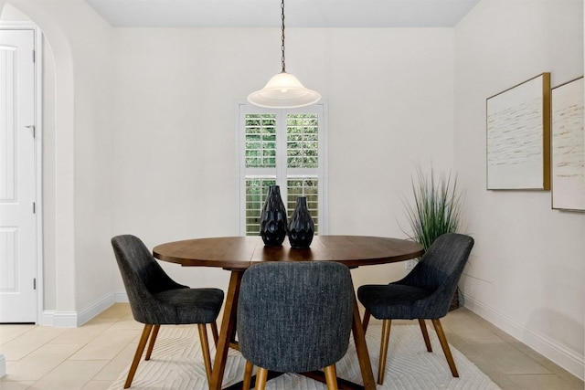 dining area with arched walkways, baseboards, and light tile patterned floors