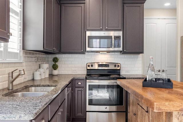 kitchen featuring stainless steel appliances, tasteful backsplash, a sink, and wood counters