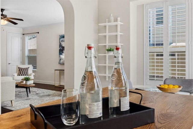 interior details featuring baseboards, arched walkways, a ceiling fan, and ornamental molding