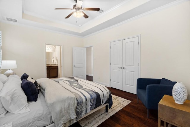 bedroom featuring dark wood-style floors, a raised ceiling, visible vents, and crown molding