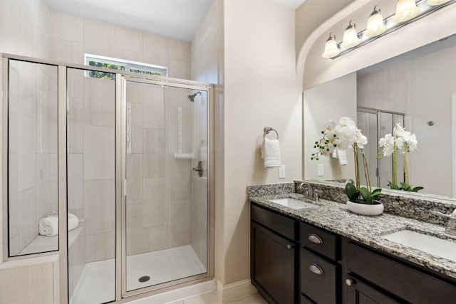 full bath with double vanity, a shower stall, and a sink