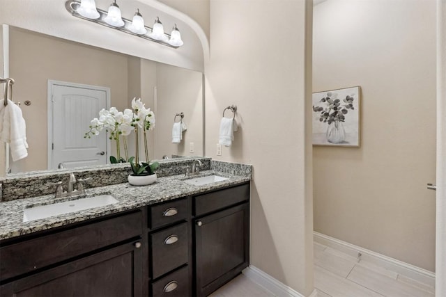 bathroom featuring double vanity, a sink, and baseboards