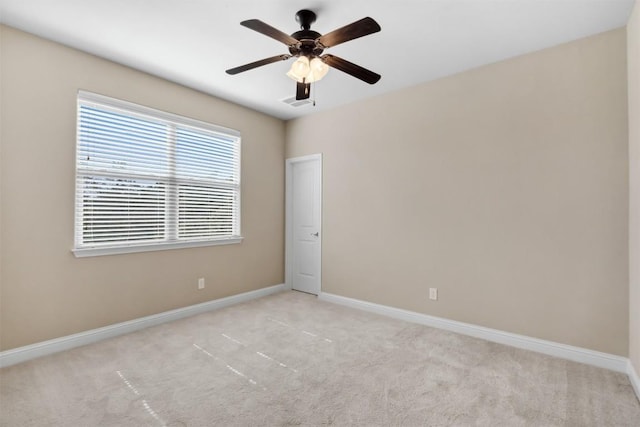 empty room featuring light colored carpet, ceiling fan, and baseboards