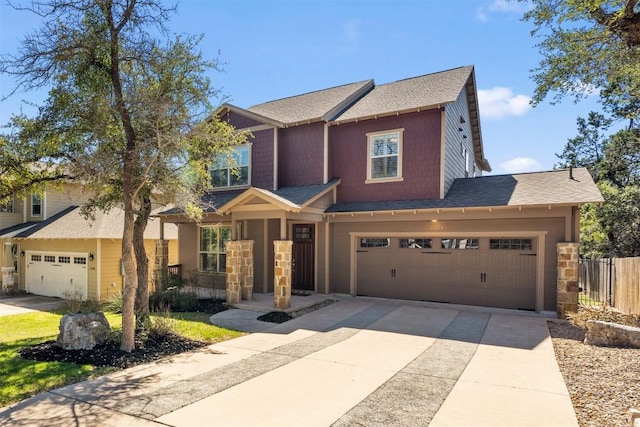 view of front of property featuring stone siding, a shingled roof, concrete driveway, and fence