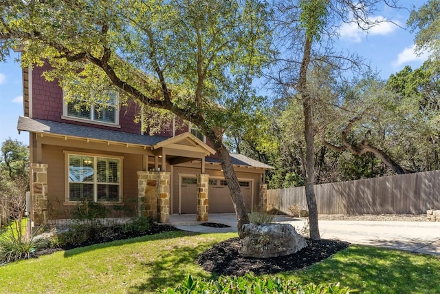 view of front of home with a garage, driveway, stone siding, fence, and a front lawn