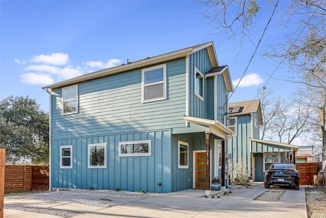 view of front of house with concrete driveway, board and batten siding, and fence