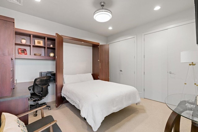 bedroom with recessed lighting, light carpet, and two closets