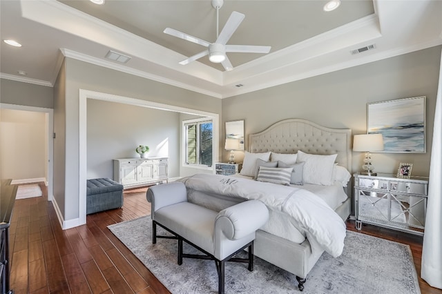 bedroom with a tray ceiling, dark wood-type flooring, visible vents, and crown molding