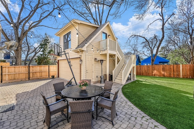 rear view of house with driveway, a patio, stairway, fence private yard, and a yard