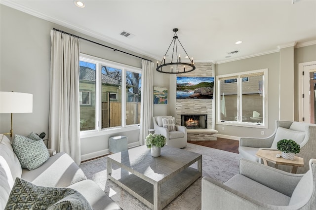 living area featuring a large fireplace, wood finished floors, visible vents, baseboards, and ornamental molding