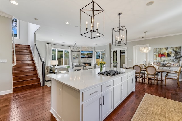 kitchen featuring stainless steel gas cooktop, a large fireplace, a kitchen island, and dark wood finished floors