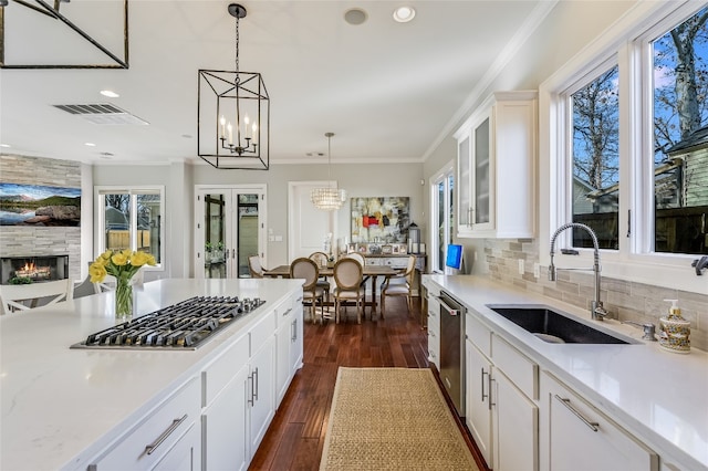 kitchen featuring tasteful backsplash, visible vents, ornamental molding, stainless steel appliances, and a sink