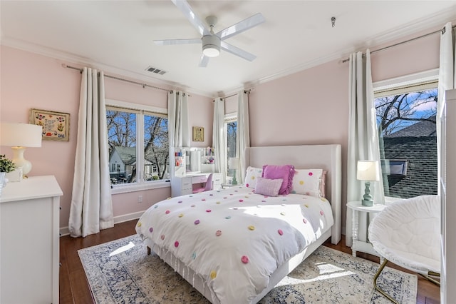 bedroom with wood finished floors, a ceiling fan, baseboards, visible vents, and crown molding