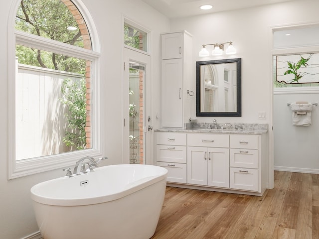 full bathroom with a soaking tub, baseboards, wood finished floors, and vanity