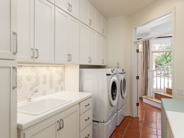 clothes washing area with cabinet space, dark tile patterned floors, washer and dryer, and a sink