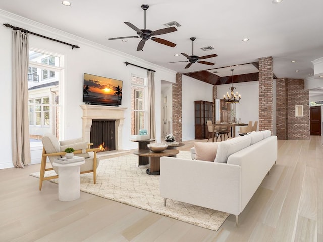 living area featuring light wood-style floors, a lit fireplace, visible vents, and ornamental molding