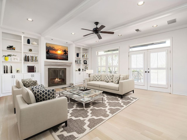 living area with built in features, french doors, crown molding, a glass covered fireplace, and wood finished floors