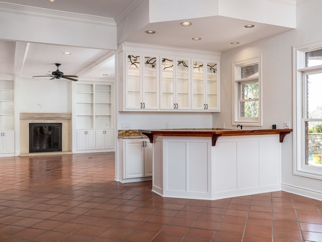 kitchen featuring glass insert cabinets, a breakfast bar, white cabinets, and a glass covered fireplace