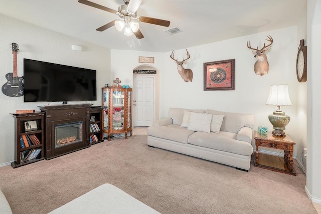 living area with baseboards, visible vents, a ceiling fan, a glass covered fireplace, and carpet