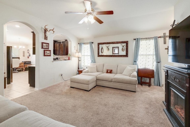 living area with arched walkways, a healthy amount of sunlight, vaulted ceiling, and light colored carpet