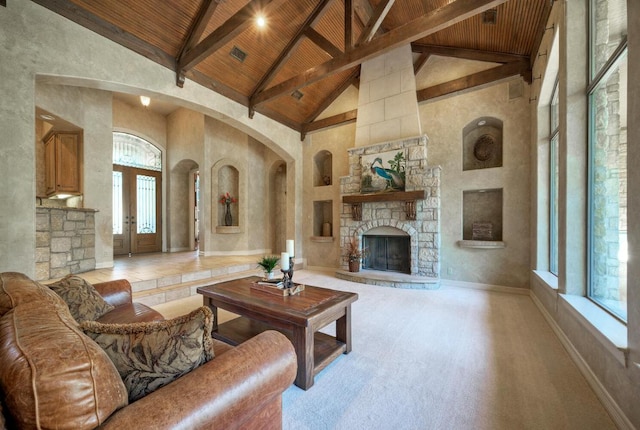 living area featuring baseboards, wood ceiling, a stone fireplace, high vaulted ceiling, and beam ceiling