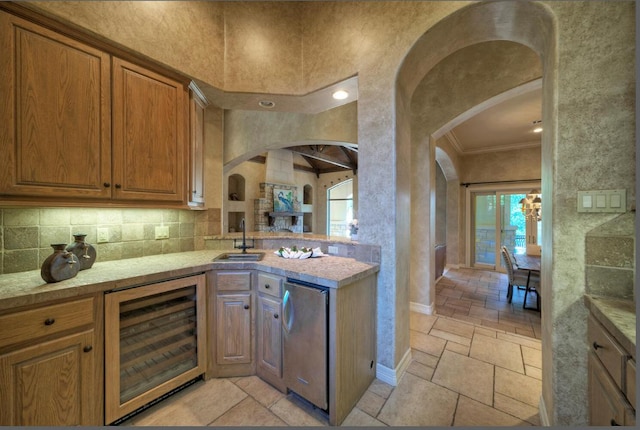 kitchen with wine cooler, a sink, light countertops, fridge, and stone tile flooring