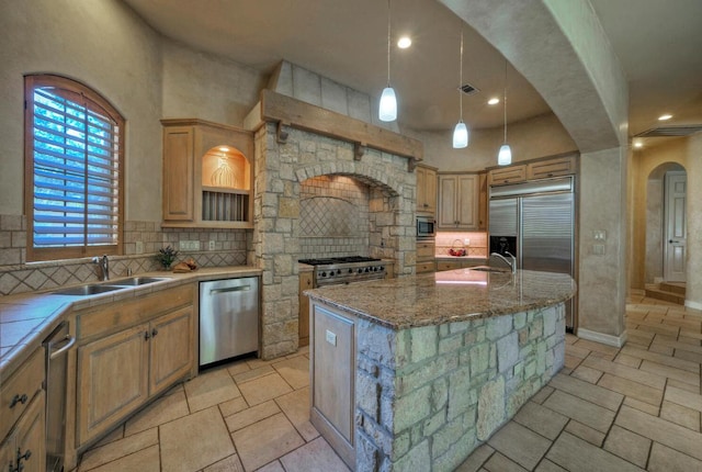 kitchen featuring built in appliances, arched walkways, backsplash, and a center island with sink