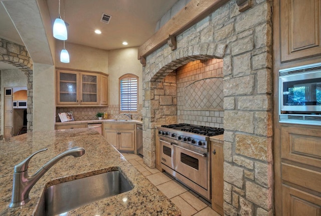 kitchen with appliances with stainless steel finishes, visible vents, a sink, and backsplash