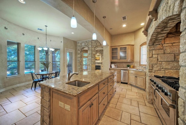 kitchen featuring visible vents, a kitchen island with sink, stone tile flooring, double oven range, and a sink