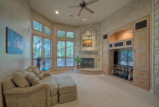 living area featuring a stone fireplace, recessed lighting, carpet floors, visible vents, and a ceiling fan