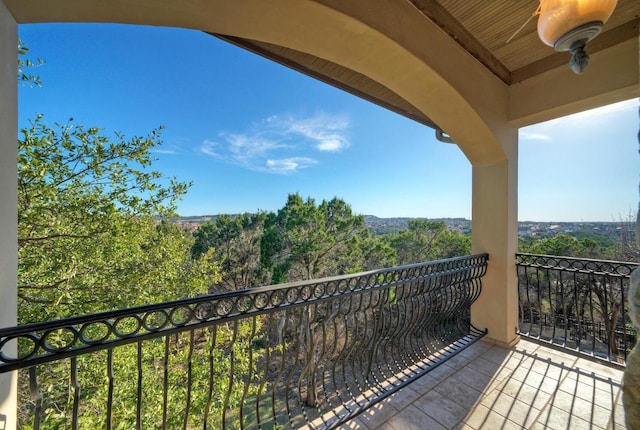 balcony featuring ceiling fan and a view of trees