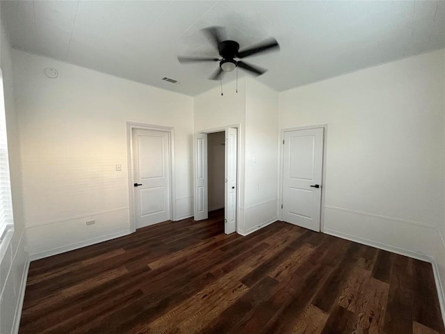 unfurnished bedroom featuring a ceiling fan, dark wood-style flooring, visible vents, and baseboards